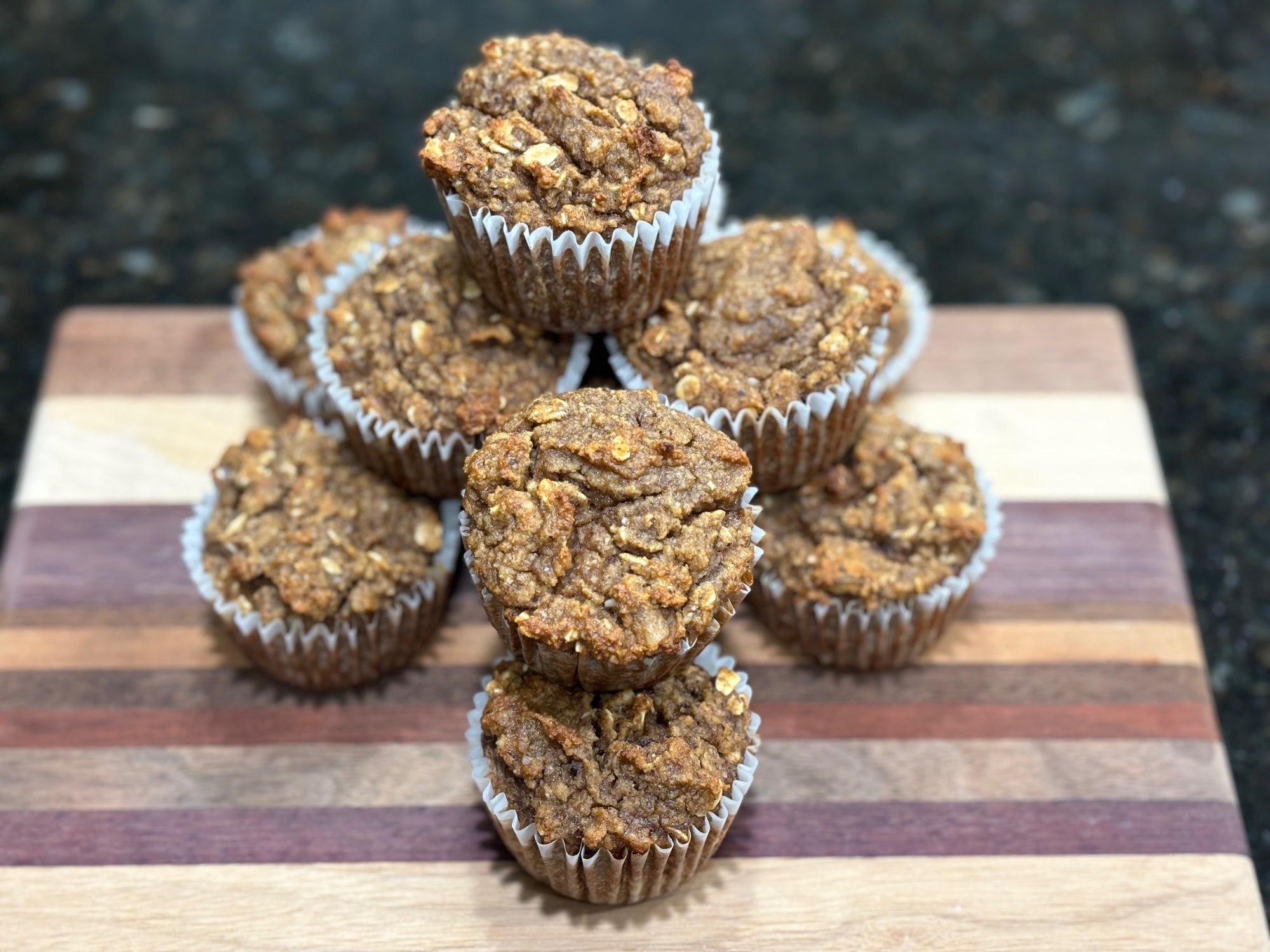 Moist gluten-free muffins sit on a wooden cutting board.