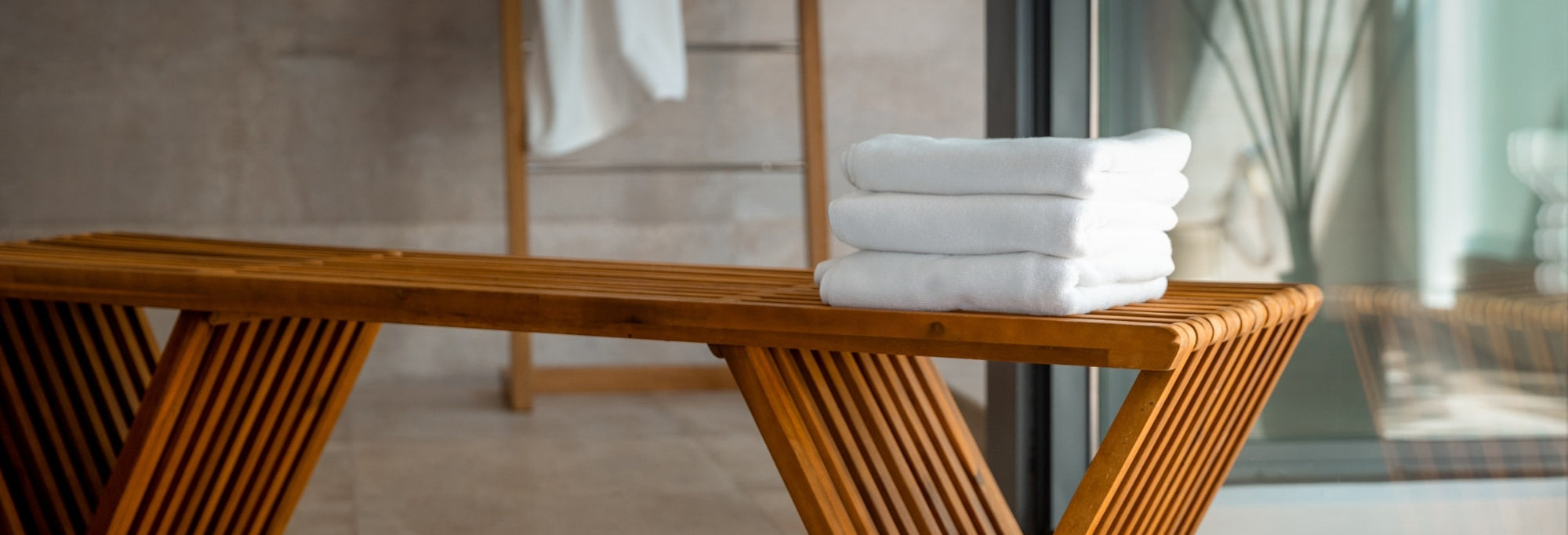 Organic terry bath mats sit on a warm wood bathroom bench at a luxury spa in Florida.