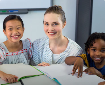 A teacher and two young pupils are smiling while working together, symbolic of the need to provide discounts for teachers.